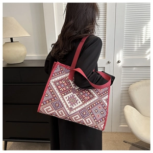 Detailed ethnic geometric woven canvas tote bag with wide red shoulder strap on model