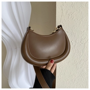 Detail of brown leather crescent bag showing smooth texture and golden metal zipper