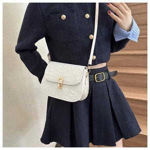 Detailed view of white floral embossed crossbody bag with golden horseshoe buckle on model