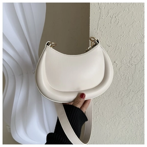 Detail of minimalist cream crescent bag showing smooth leather texture and gold hardware