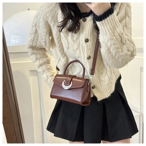 Detail of vintage dark brown crossbody bag with silver moon buckle worn by a model