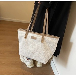 Detail of soft white plush tote bag with brown leather handles and fashion logo tag