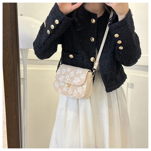 Detail of floral embroidered beige crossbody bag with gold horseshoe buckle closure