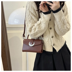 Detail of brown leather crossbody bag with silver crescent moon buckle and handle