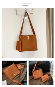 Detail of brown litchi pattern leather bag set with wide strap and golden turn-lock