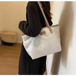Detail of white plush tote bag with brown leather handles worn with black blazer
