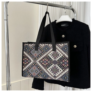 Detail view of ethnic geometric woven pattern and black handles on a canvas tote bag