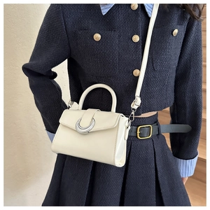 Chic cream leather crossbody bag with silver crescent ring detail worn by a model