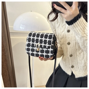Detail einer schwarz-weißen Plaid-Umhängetasche aus Tweed mit goldenem Hufeisenschloss