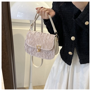 Detail view of beige pleated texture handbag featuring a golden horseshoe metal clasp