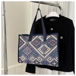 Detail of ethnic geometric patterned canvas tote bag with navy blue woven handle