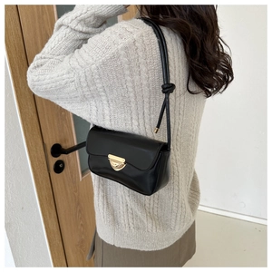 Detail of a black PU leather crossbody bag featuring a gold triangle lock and knotted strap