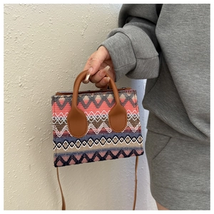 Close-up of ethnic woven mini bag with multi-color wave patterns and leather handles