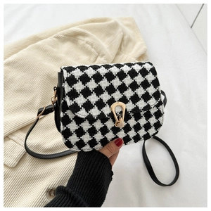 Detail of wool houndstooth plaid crossbody bag with golden metal lock and strap