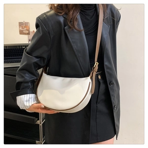 White crescent crossbody bag with brown trim shown in a stylish office commuter setting