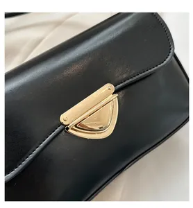 Close-up of golden triangular metal lock on black vintage leather shoulder bag