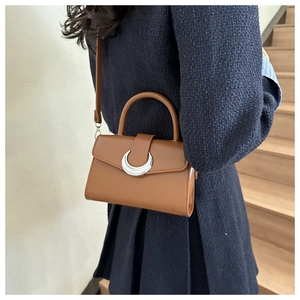 Brown vintage square bag with a silver crescent buckle worn by a model on a staircase