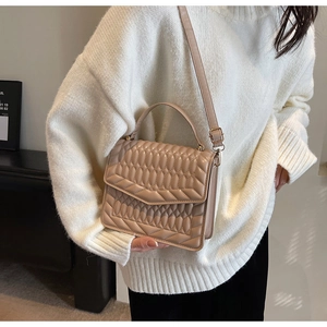 Beige gewatteerde kleptas met handvat gedragen bij een witte gebreide trui in casual stijl