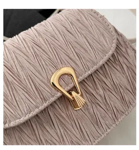 Close-up of pleated champagne pink texture and golden U-shaped lock on luxury small square bag