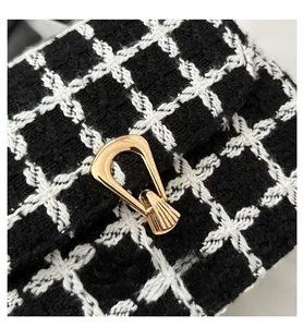 Detail der Tweed-Karotasche mit eleganter goldener U-Schnalle und Stoffstruktur