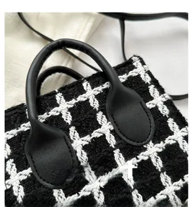 Detailed view of the black and white tweed fabric and smooth leather handle of the handbag