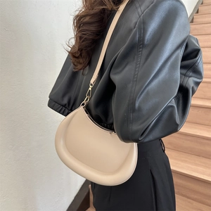 Minimalist beige crescent shoulder bag with gold hardware and sleek half-moon silhouette