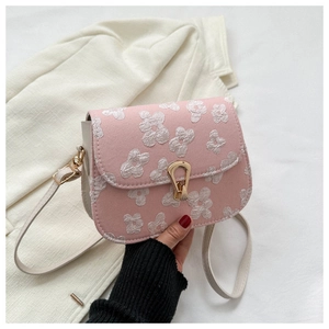 Detail of pink floral embroidered flap bag with a golden teardrop clasp and leather strap