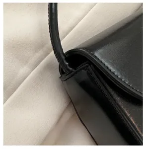Close-up of premium stitching and leather strap connection on black crossbody bag