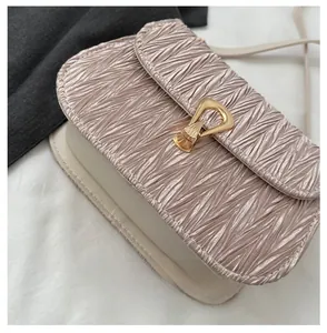 Detail of pleated texture flap and gold metal buckle on two-tone crossbody bag