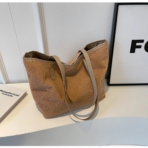 Close-up of brown faux shearling tote bag featuring long leather straps and soft curly texture