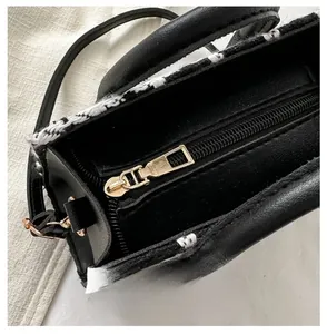 Detailed close-up of smooth gold metal zipper and tweed texture on black leather bag