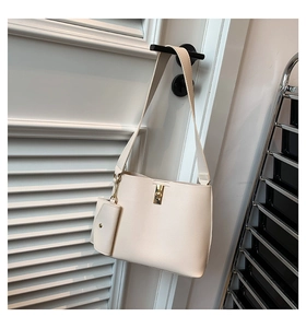 Detail of cream tote bag with small zipper pouch and gold twist lock on white door