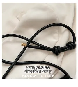 Detail of black leather knotted strap with elegant gold metal tips on a square bag