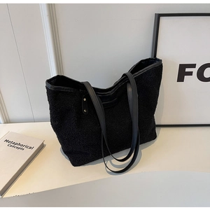 Close-up of black faux shearling texture and synthetic leather strap on tote bag