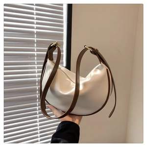 Detailed view of white hobo bag with contrast brown leather strap and gold buckle