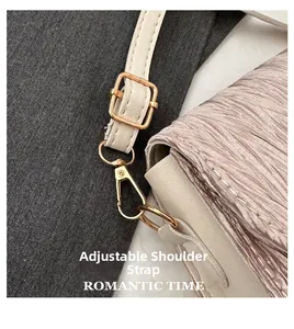 Detail of adjustable strap with gold-tone hardware on pleated crossbody handbag