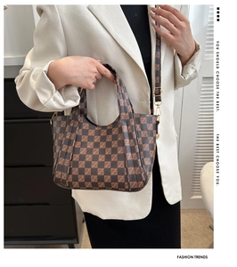 Detail of vintage brown checkered bucket bag with dual handles and adjustable strap