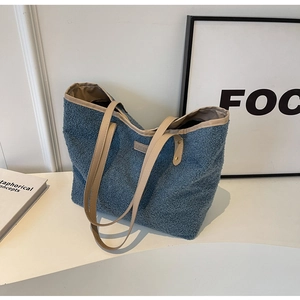 Detailed top view of light blue plush tote bag with PU straps on a white desk
