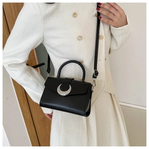 Detail of a vintage black square bag featuring a silver crescent buckle and smooth leather