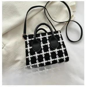 Detail of tweed plaid mini bag with leather handles and gold metal hardware