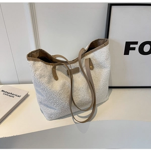 Detail of plush off-white tote bag with brown leather trim and fashion brand tag