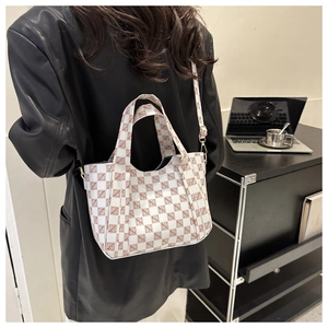 Back view of a model wearing a plaid tote bag showing its size and styling with a leather jacket