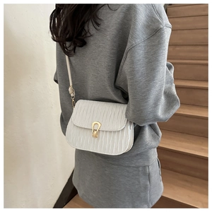 Detail of white pleated faux leather crossbody bag with elegant golden horseshoe lock