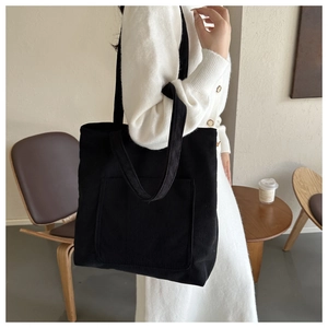 Détail du sac cabas en velours côtelé noir avec poche avant et texture à fines côtes