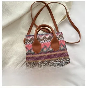Ethnic style woven square bag next to a smartphone showing compact size and texture