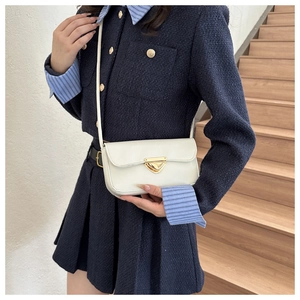 Close-up of white leather crossbody bag with elegant gold triangle metal buckle clasp