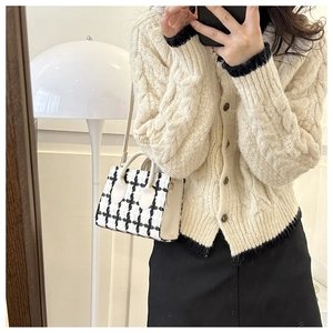 Detail of checkered small square handbag with round handle and knit cardigan outfit