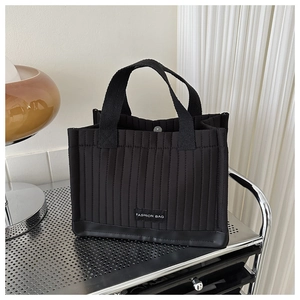 Detail of black quilted tote bag with vertical stitching and Fashion Bag label