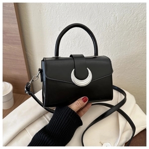 Detail of a vintage black matte leather crossbody bag with a silver moon buckle accent