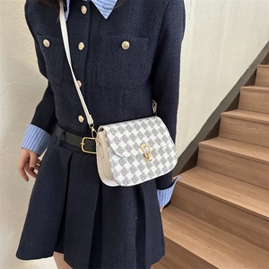Quilted crossbody bag with grey houndstooth pattern and gold horseshoe clasp on model